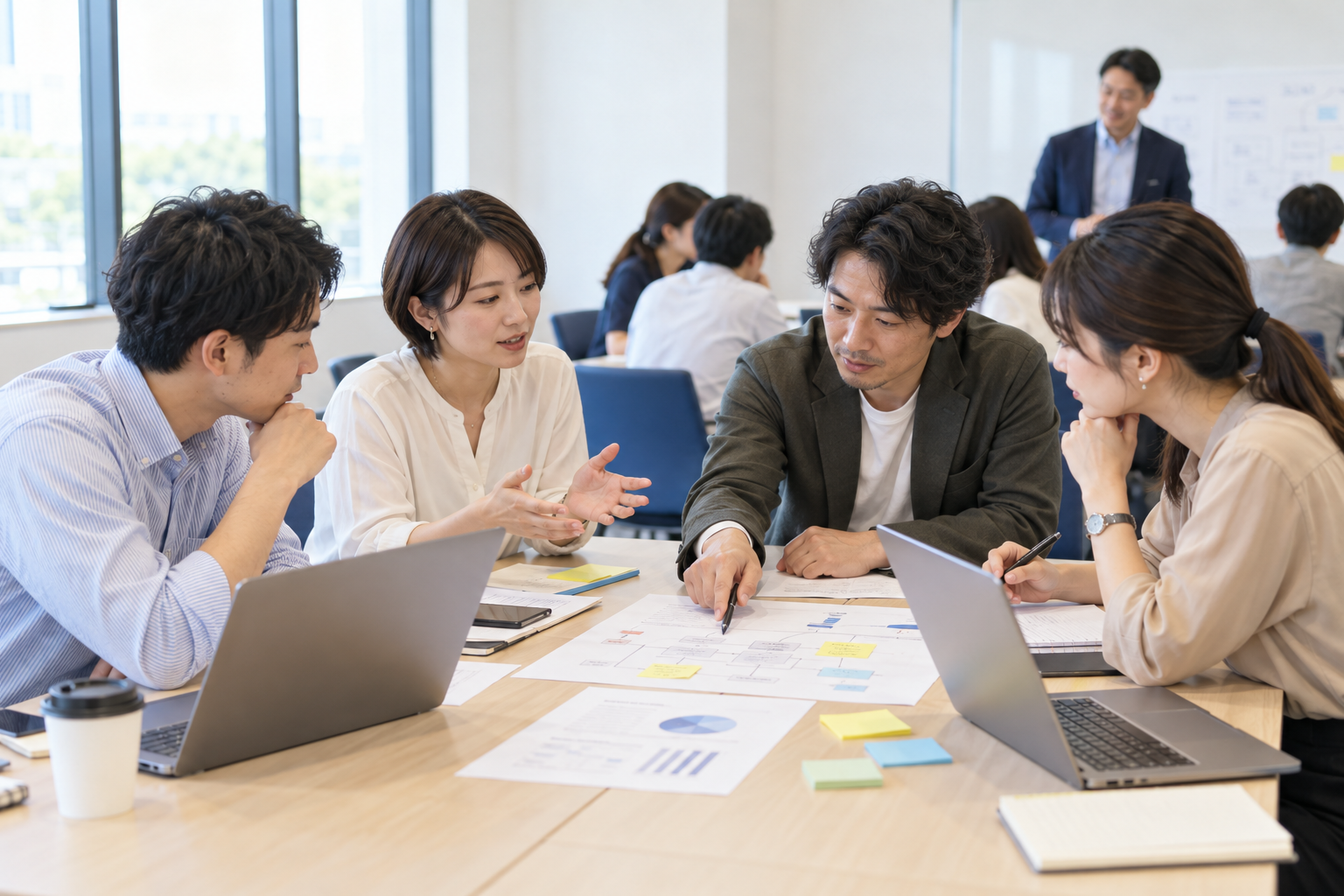 受講者が資料とPCを囲み、話し合いながら演習に取り組んでいる研修風景